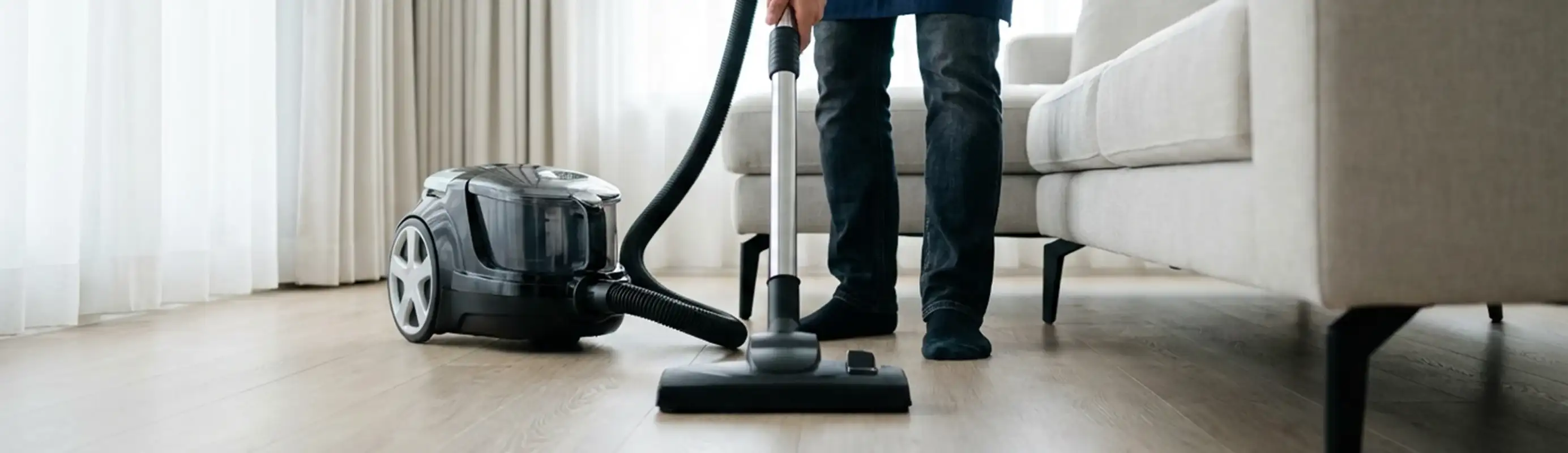 Professional house cleaner vacuuming a living room floor with a canister vacuum cleaner, Chattanooga, TN.